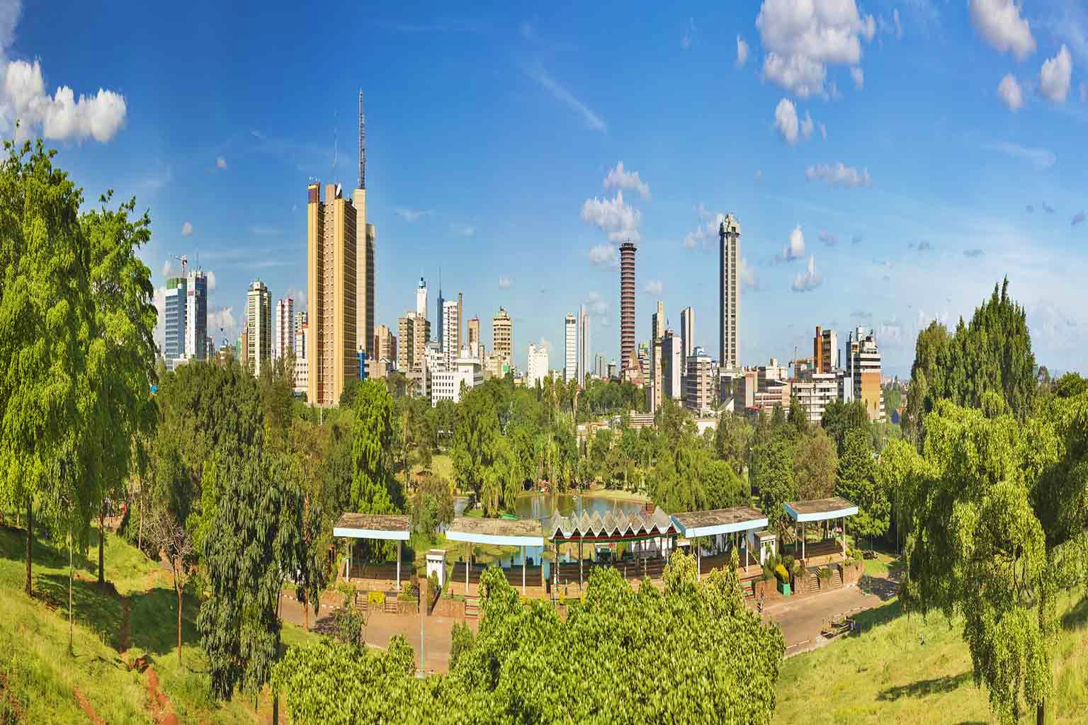 Nairobi skyline with tall buildings viewed from green park with trees and pond in foreground
